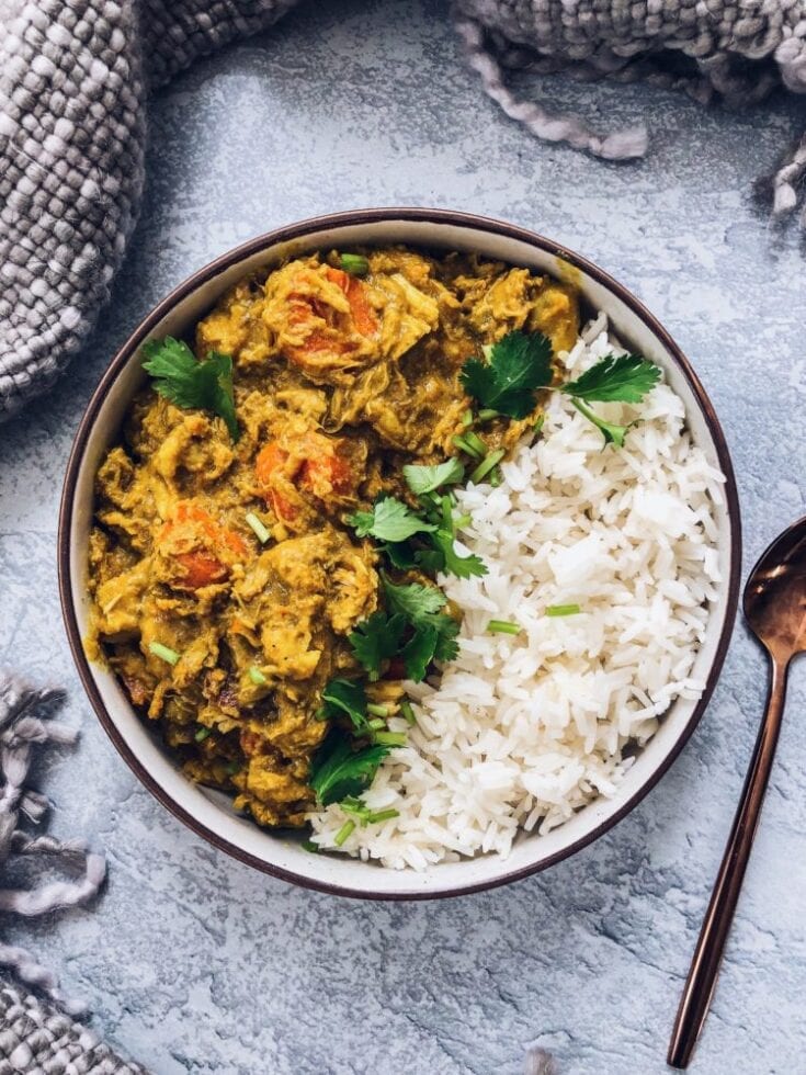A bowl of jasmine rice and Thai Coconut Curry Chicken. There is a fork on the side.