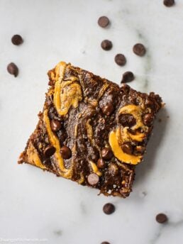 1 piece of sweet potato paleo brownies with almond butter swirl and chocolate chips on top.
