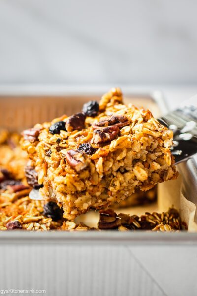 A spatula is serving a piece of freshly baked carrot cake oatmeal bars. This gluten free vegan carrot cake appears to be soft and chewy, perfect for Easter brunch.