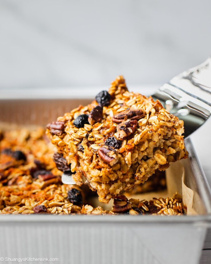 A spatula is serving a piece of freshly baked carrot cake oatmeal bars. This gluten free vegan carrot cake appears to be soft and chewy, perfect for Easter brunch.