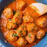 Paleo Italian Meatballs with Creamy Tomato Sauce with a wooden spoon in the pan and fresh basil sprinkled on top
