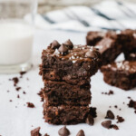 Fudgy Gooey Healthy Brownies stacked up with more brownies and a glass of milk.