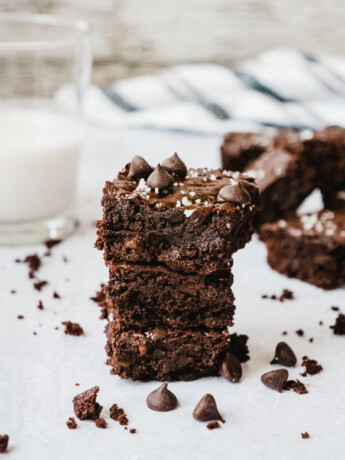 Fudgy Gooey Healthy Brownies stacked up with more brownies and a glass of milk.