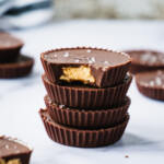 4 peanut butter cup stack on top of each other. There are peanut butter coming out of hte chocolate shell.