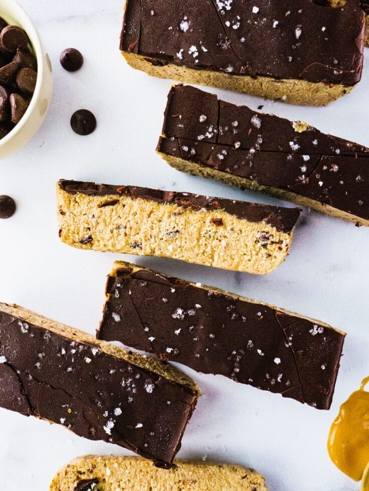 No Bake Chocolate Chip Cookie Dough Bars |Gooey and Sweet Chocolate Chip Cookie Dough layered with dark chocolate and sprinkles of sea salt on a piece of marble.