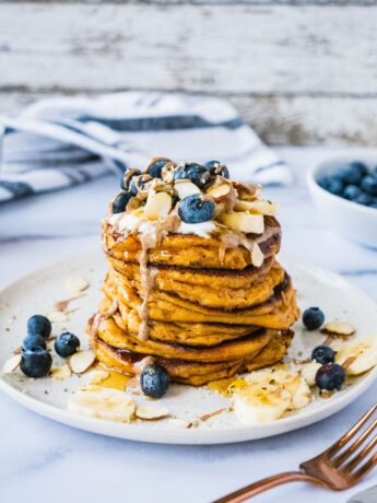 almond flour pancakes topped with blueberry banana, almonds, nut butter and maple syrup.