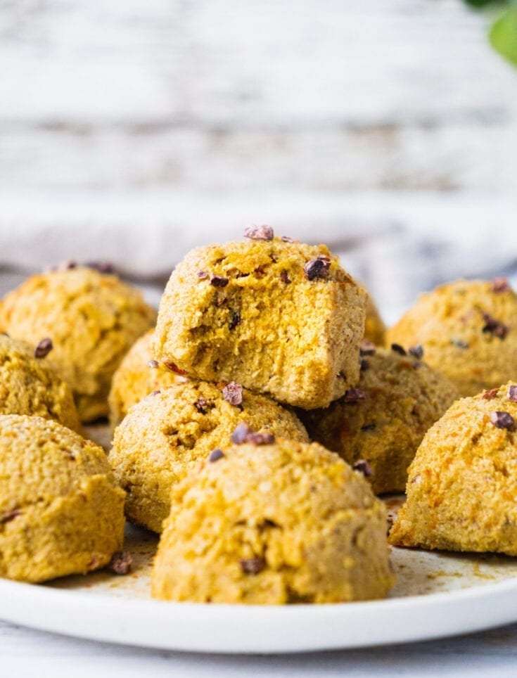 A plate of pumpkin spice energy balls. One of the fat bombs has a bite. The texture is gooey and soft.