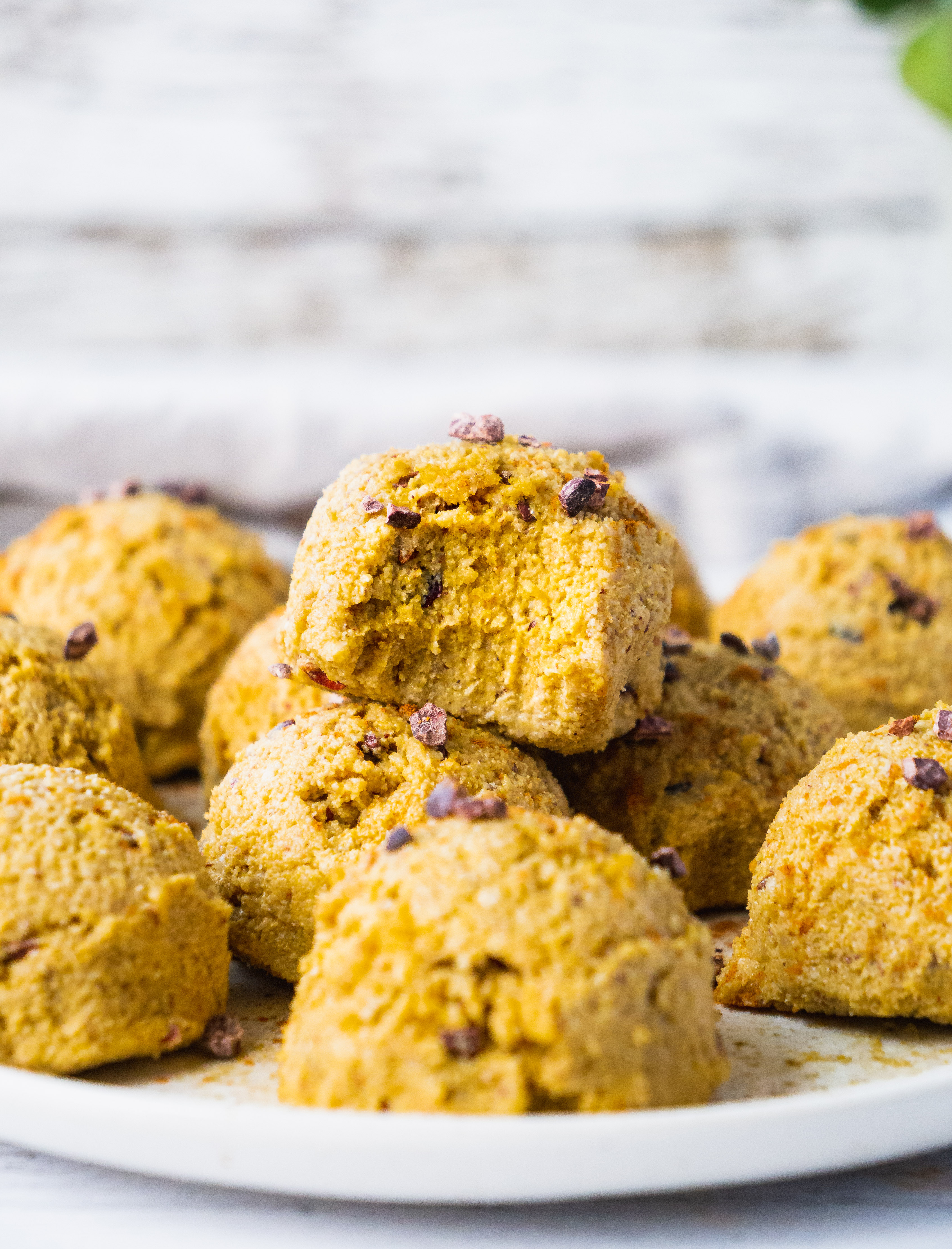 A plate of pumpkin spice energy balls. One of the fat bombs has a bite. The texture is gooey and soft.