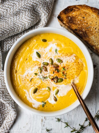 A bowl of healthy butternut squash soup topped with dairy free coconut milk, rusty sourdough, roasted pumpkin seeds. This easy butternut squash bisque recipe can be made all in one blender.