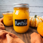 a jar of fresh homemade pumpkin puree from scratch. There is a pumpkin in the background.