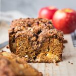 A loaf of sliced paleo apple cinnamon bread. There are some apple chunks in the middle of the sliced apple bread. This easy apple recipe is perfect for the fall season.