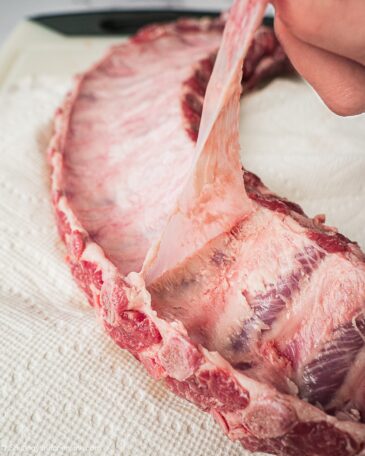 Pulling off the membrane of the rib in order to prepare for cooking.