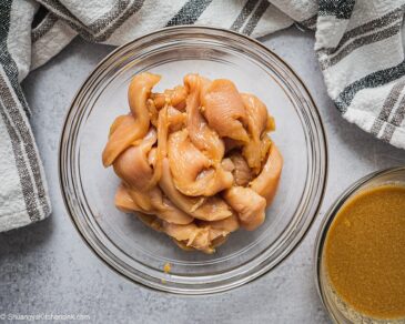 A bowl of chicken breast marinated in coconut aminos.