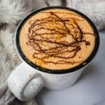 A mug of homemade mocha Latte with melted chocolate on top and sprinkle of cinnamon. It is very frothy.