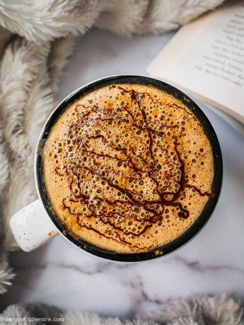 A mug of homemade mocha Latte with melted chocolate on top and sprinkle of cinnamon. It is very frothy.