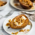 A plate of whole baked pears stuffed with vegan yogurt, granola, honey and walnuts and nut butter. Oven baked pears are spiced with cinnamon.