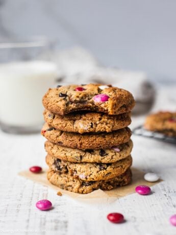 A stack of eggless chocolate chip cookies with M&Ms that can be made vegan, keto and paleo. Perfect healthy cookies for Valentine's Day. There are extra M&Ms on the table.