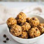 A plate of peanut butter oatmeal balls. There are a few chocolate chips on the plate and table.