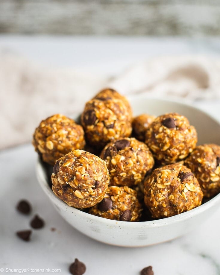 A plate of peanut butter oatmeal balls. There are a few chocolate chips on the plate and table.