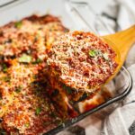 Freshly Bake Eggplant Parmesan just came out of the oven. There is a spoon holding up one piece.