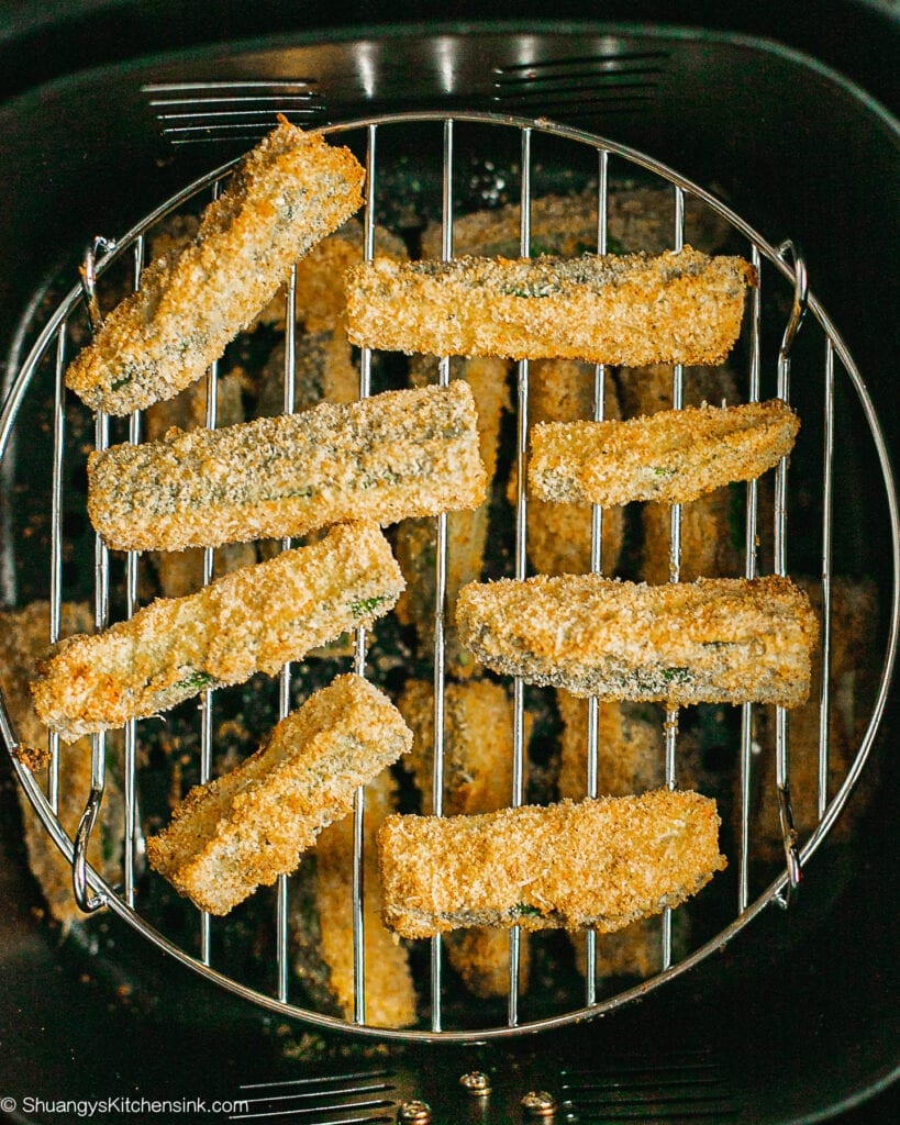 Zucchini Fries in an air fryer basket. The color appears to be golden brown.