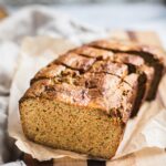 A loaf of zucchini banana bread on a piece of wood board. They are sliced.