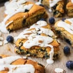 A few paleo blueberry scones with cashew cream cheese frosting. There are a few blueberries and almonds on the side.