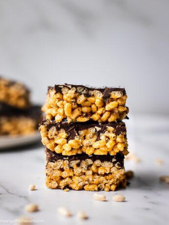 A stack of peanut butter rice crispy treats with peanut butter. There is a plate of them in the back as well.