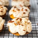 Freshly baked pumpkin spice donuts on a cooling rack ready to be glazed. They are packed with pumpkin spice, almond flour, pumpkin puree. It is topped with paleo, gluten free maple cashew icing and sprinkle of pecans.