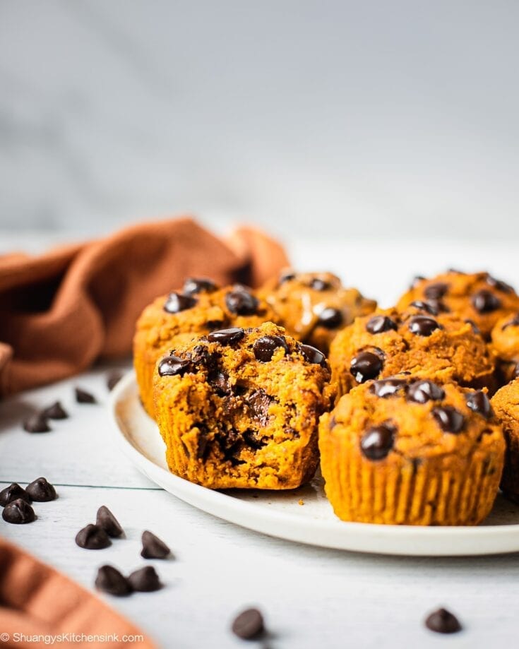 A plate of vegan whole wheat pumpkin muffins. The middle one has a bite in it. The most Moist and fluffy pumpkin muffin this fall.