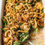 A pan of easy green bean casserole that has gluten free crispy onion on top, and cream mushroom soup with baked green greens.