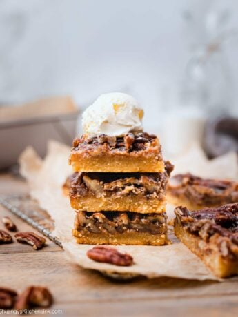 three squares of pelao pecan pie bars on top of each other topped with dairy free ice cream