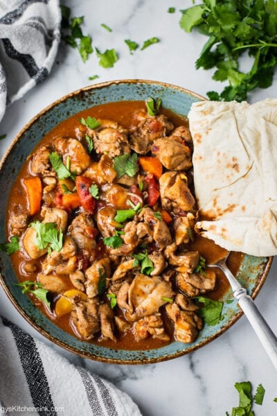A plate of keto butter chicken that is cooked in flavorful Indian Spiced sauce in the instant pot. It has cilantro on top for garnish. it is served with gluten free naan bread.