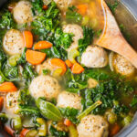 A pan of stove top gluten free dairy free soup using this easy Italian Wedding Soup recipe. There are baked chicken meatballs, celery, kale and carrots.