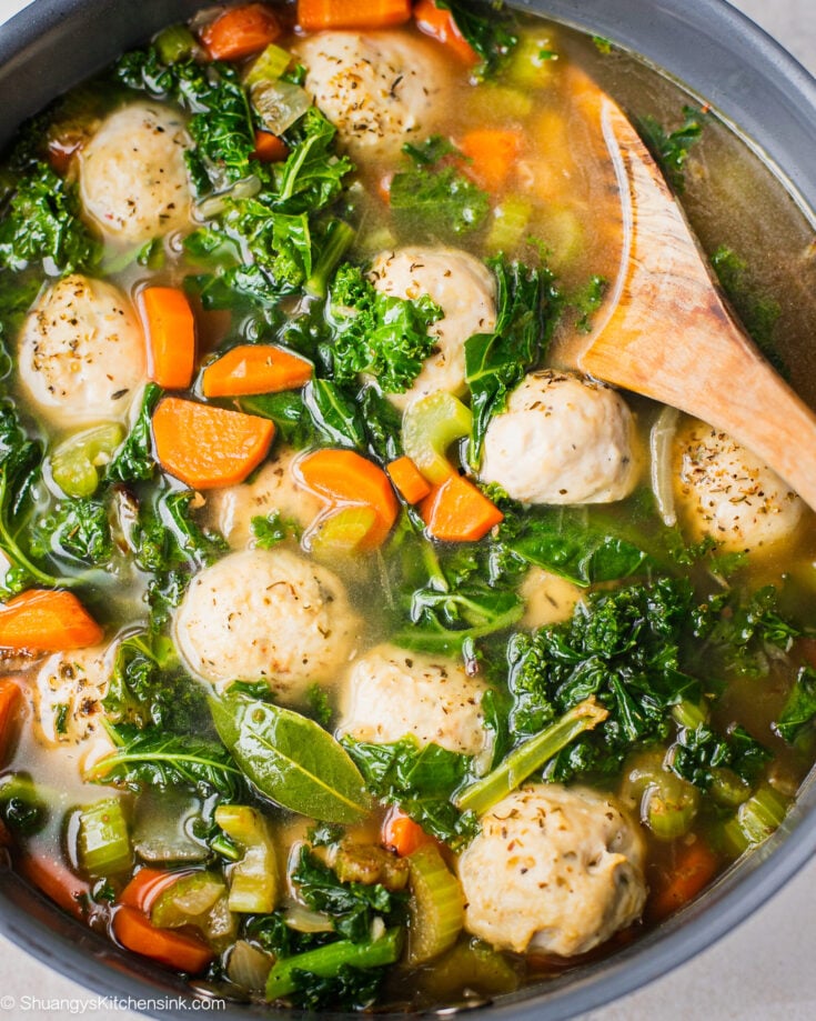 A pan of stove top gluten free dairy free soup using this easy Italian Wedding Soup recipe. There are baked chicken meatballs, celery, kale and carrots.