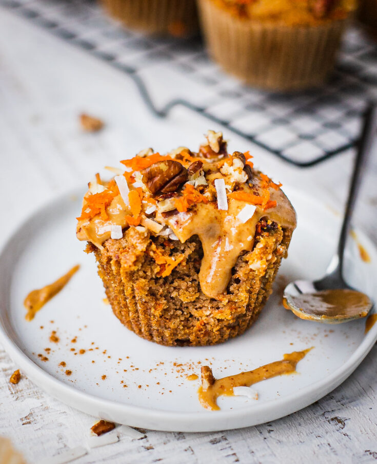 A gluten free carrot cake muffin cut in half. Half of the carrot muffin is topped with almond butter which makes a great healthy breakfast option.
