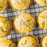 A batch of gluten-free lemon poppyseed muffins on a cooling rack. There is coconut icing on the healthy lemon poppyseed muffins.