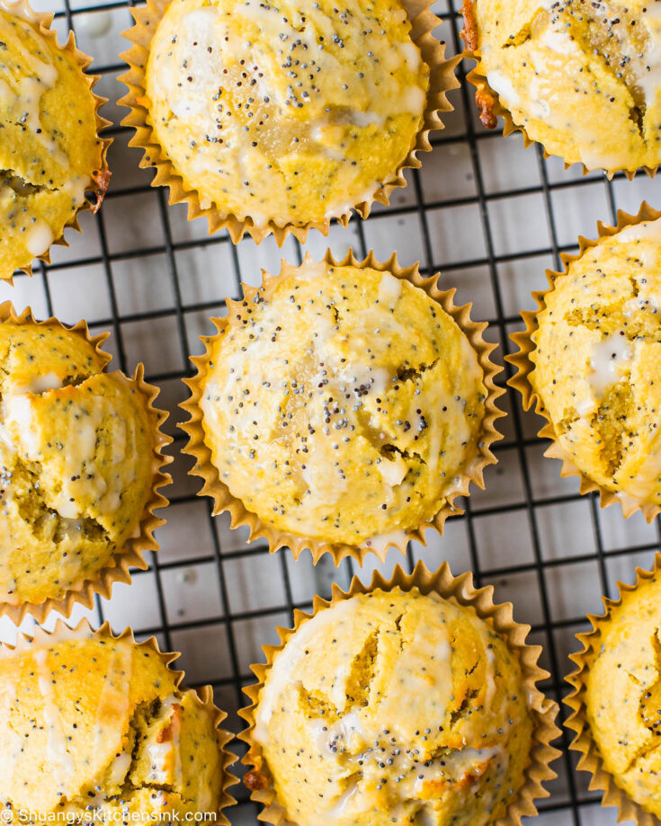 A batch of gluten-free lemon poppyseed muffins on a cooling rack. There is coconut icing on the healthy lemon poppyseed muffins.