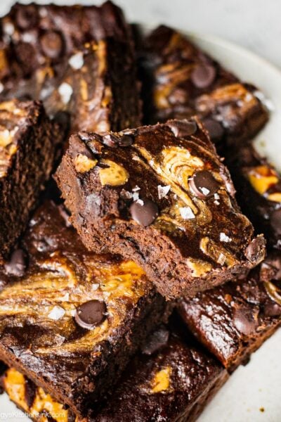 Fudgy flourless banana brownies drizzled with almond butter and topped with vegan chocolate chips