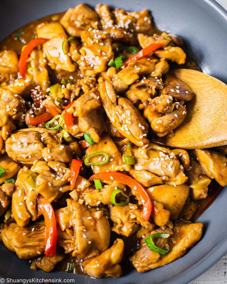 A pan of chicken red bell peppers, green onion, healthy Chinese stir fry sauce sprinkled with toasted sesame seeds
