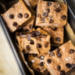 There are a pile of no bake cookie dough bites topped with dairy free chocolate chips and flaky salt