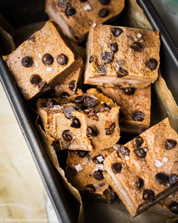 There are a pile of no bake cookie dough bites topped with dairy free chocolate chips and flaky salt