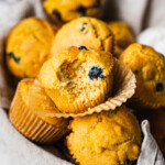 There are many cornbread muffins. Someone has taken a bite from he one in the front. There is honey drizzled on the dessert
