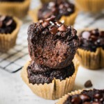 Double chocolate banana muffins that are rich and gooey from all the chocolate. There is a bite taken from one of the muffins so you can see how chocolatey it looks on the inside.