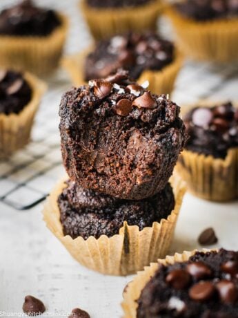 Double chocolate banana muffins that are rich and gooey from all the chocolate. There is a bite taken from one of the muffins so you can see how chocolatey it looks on the inside.