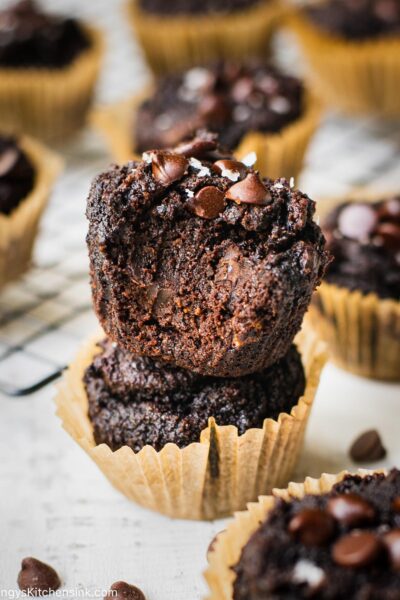 Paleo Double chocolate banana muffins that are rich and gooey from all the chocolate. There is a bite taken from one of the muffins so you can see how chocolatey it looks on the inside.