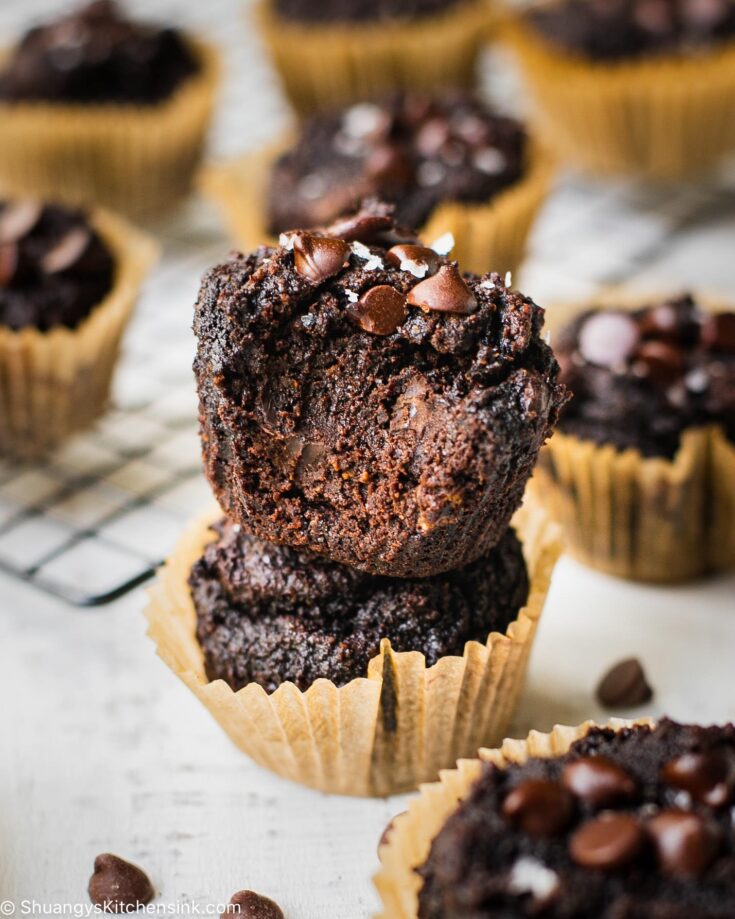 Paleo Double chocolate banana muffins that are rich and gooey from all the chocolate. There is a bite taken from one of the muffins so you can see how chocolatey it looks on the inside.