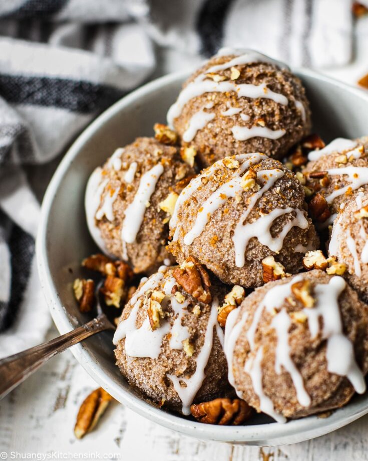 No bake Cinnamon roll cookie dough balls sprinkled with pecans in a round white ball.