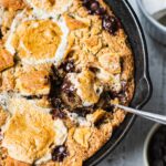 a spoon is digging into a giant s'mores cookie skillet.