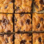 A pan of freshly baked pumpkin pie chocolate chip cookie bars on a cutting board. The healthy bread has been cut into nine squares.
